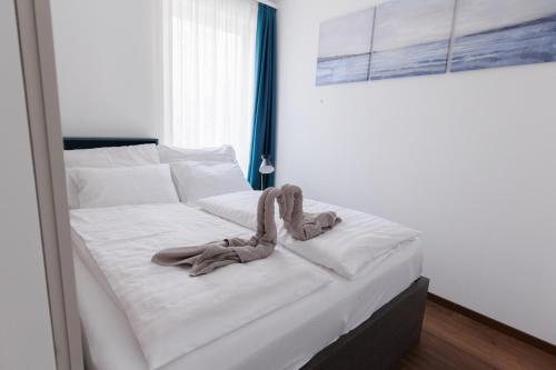 ein Schlafzimmer mit einem weißen Bett mit weißer Bettwäsche in der Unterkunft Villa Bauhaus Wellness Apartman 102 in Siófok