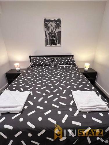 a bedroom with a black and white bed with two night stands at Black & White Delight - 2bd 2bth Apt - Braddon in Canberra
