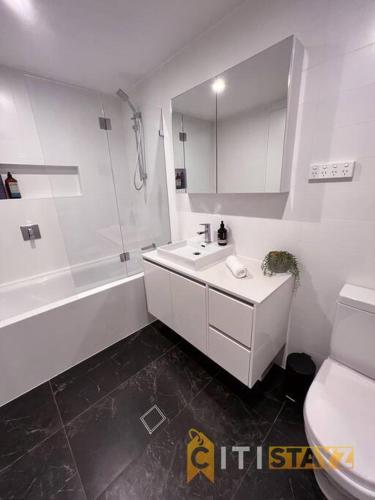 a bathroom with a sink and a shower and a toilet at Black & White Delight - 2bd 2bth Apt - Braddon in Canberra