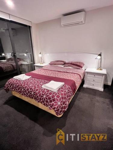 a bedroom with a bed with a red comforter at Black & White Delight - 2bd 2bth Apt - Braddon in Canberra