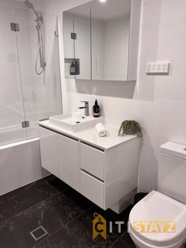 a white bathroom with a sink and a toilet at Black & White Delight - 2bd 2bth Apt - Braddon in Canberra