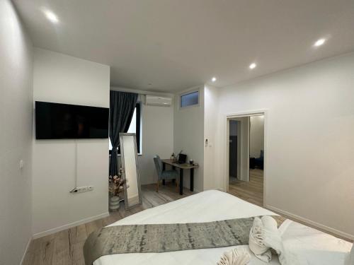 a white bedroom with a bed and a desk in it at V Apartment Šibenik in Šibenik