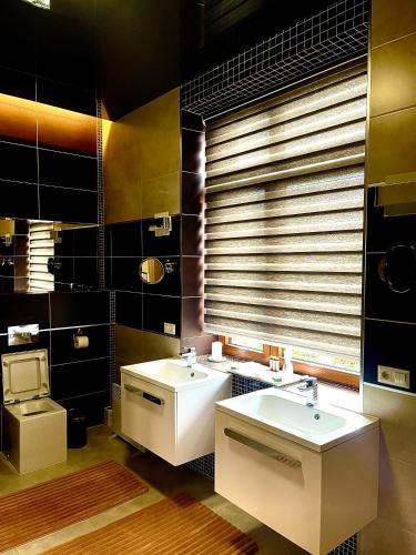 a bathroom with two sinks and a window with blinds at Villa Sofia in Odesa