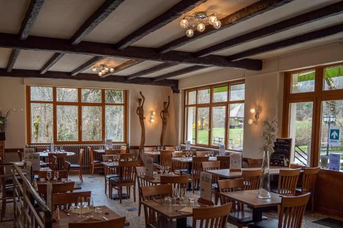 un restaurant avec des tables et des chaises en bois et des fenêtres dans l'établissement Au Gai Soleil du Mont-Aiguille, à Chichilianne