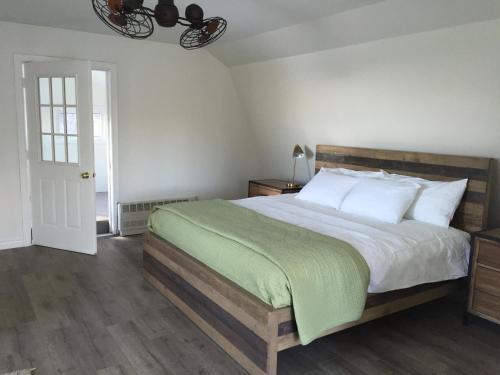 a bedroom with a large bed with a green blanket at The Trails Retreat (Private Cabin) in Orangeville