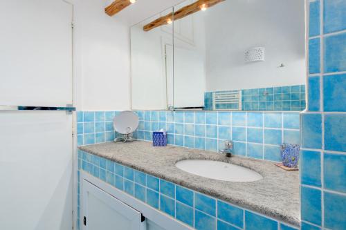 Baño de azulejos azules con lavabo y espejo en Private Villa ORIONE, en Porto Cervo