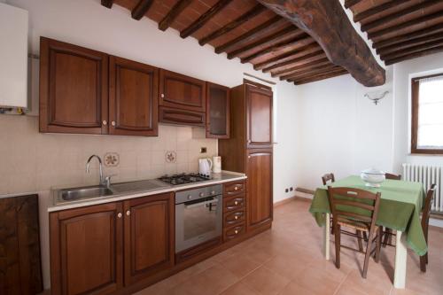 a kitchen with wooden cabinets and a table with a green table at Ulivo-Chianti Charming Flat with Private Parking! in Asciano