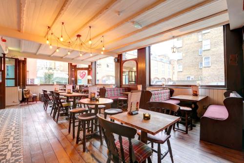 a restaurant with tables and chairs and a large window at PubLove @ The Exmouth Arms, Euston in London