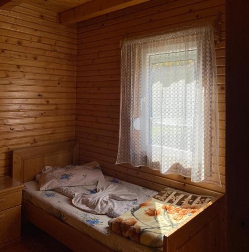 a bed in a wooden room with a window at Ethno village & resort Ćorić in Mojkovac