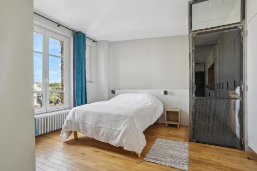 a white bedroom with a bed and a large window at Le Saint Charles - Versailles in Versailles