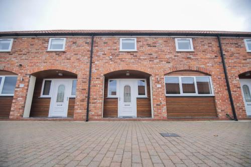 a brick building with two white doors on it at Murton Grange in York