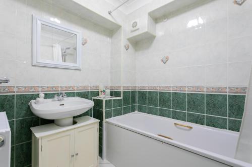 La salle de bains est pourvue d'un lavabo, de toilettes et d'une baignoire. dans l'établissement West Hill Stays Chapel Alleton LS7 - 3 bed Sleeps 5 - close to City Center - free parking - contractor welcome, à Moortown