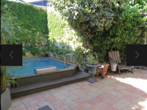 einen Pool in einem Garten neben einer Hecke in der Unterkunft Maison climatisée avec stationnement et wifi in Bram