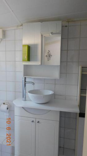 une salle de bain blanche avec un lavabo et un miroir dans l'établissement la garrigue, à Villeneuve-lès-Avignon