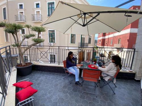 two women sitting at a table under an umbrella at Zara Palace in Scafati