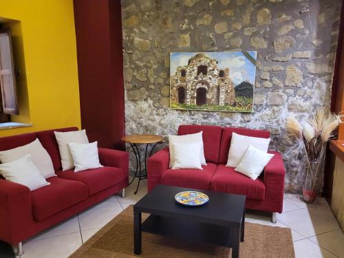 a living room with two red couches and a table at Hotel Federico II in Castiglione di Sicilia