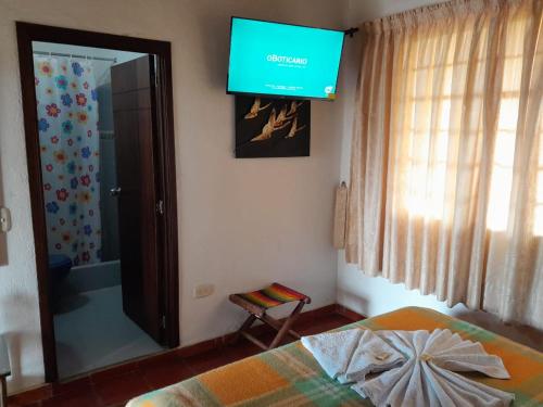 a bedroom with a flat screen tv on the wall at Villa Liliana Lodge Mesa de los Santos in Los Santos