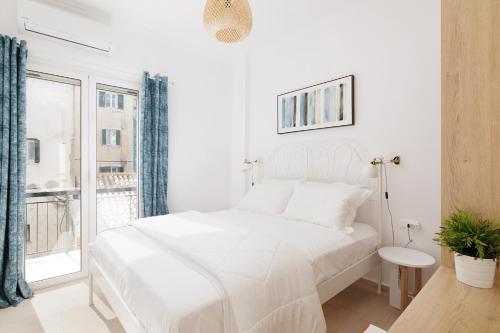 um quarto branco com uma cama branca e uma janela em Old courthouse apartment em Corfu Town