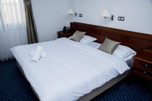 a bedroom with a large white bed with two towels on it at Hotel Hum in Ljubuški