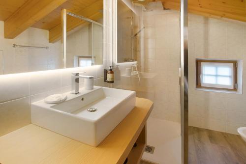 La salle de bains blanche est pourvue d'un lavabo et d'une douche. dans l'établissement Chalet La Marinella Rododendro, à Livigno