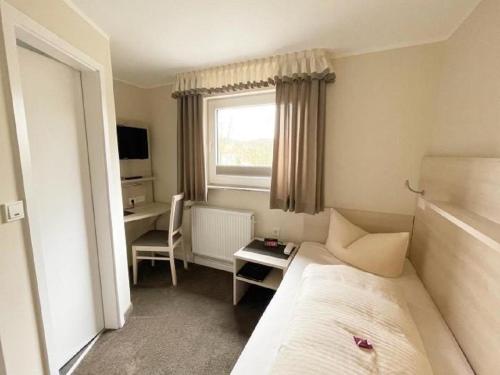 a hotel room with a bed and a desk and a window at Hotel-Garni Haus Johanna in Einbeck