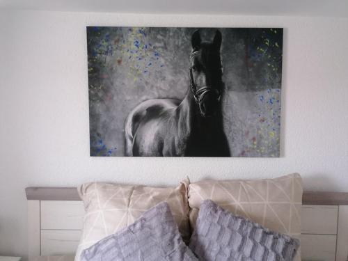 une peinture d'un cheval sur un mur au-dessus d'un lit dans l'établissement "Die Jockeysuite" auf unserem Reiterhof, à Birkenbeul