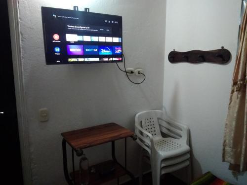 a tv hanging on a wall with a table and a chair at Villa Liliana Lodge Mesa de los Santos in Los Santos