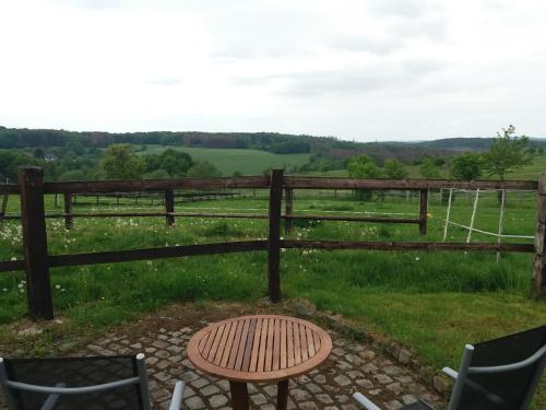 a wooden fence with a table and chairs in front of a field at "Die Jockeysuite" auf unserem Reiterhof in Birkenbeul