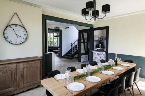 a dining room with a table and a clock on the wall at La Villa de l'Etoile 10 personnes in Forges-les-Eaux