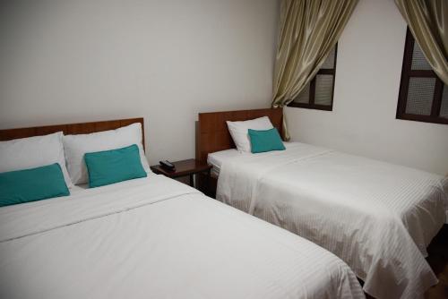duas camas sentadas uma ao lado da outra num quarto em Hotel Lili - Popayán em Popayán
