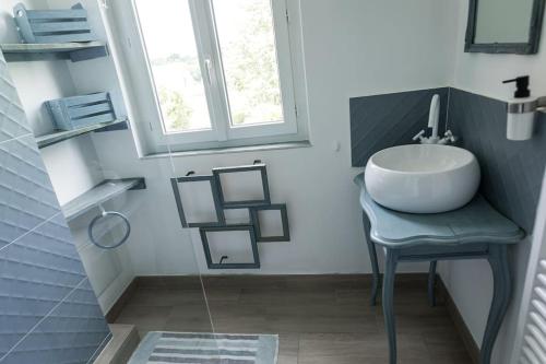 ein Bad mit einem Waschbecken, einem Tisch und einem Fenster in der Unterkunft La Villa de l'Etoile 10 personnes in Forges-les-Eaux