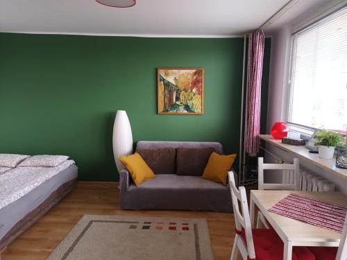 salon z kanapą i zieloną ścianą w obiekcie City Studio w mieście Częstochowa