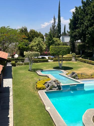una piscina en un patio con césped y árboles en La Pedrera Atlixco, 