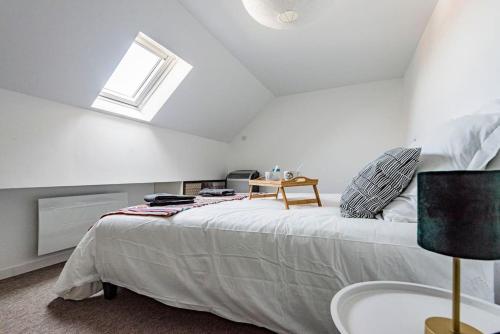 ein weißes Schlafzimmer mit einem Bett und einem Fenster in der Unterkunft Duplex LUTON 4 in Reims