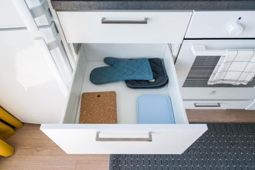 an open drawer of a white cabinet with a blue seat at Hiisi Homes Kirkkonummi Laajakallio in Kirkkonummi