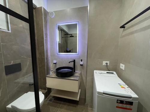 a bathroom with a sink and a toilet and a mirror at Saranda Central Apartment in Sarandë
