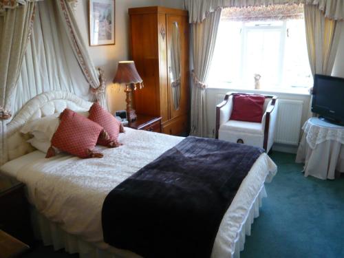 a bedroom with a bed and a chair and a television at Meryan House Hotel in Taunton