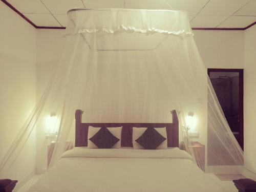 a bedroom with a bed with a mosquito net at Tantra Ella Lodge in Ella
