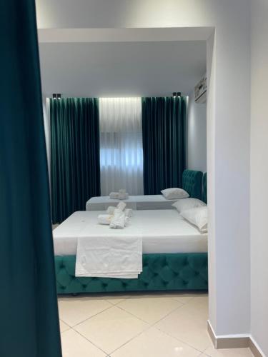 a bedroom with a large white bed with green curtains at Qeparo Napolon Complex in Qeparo