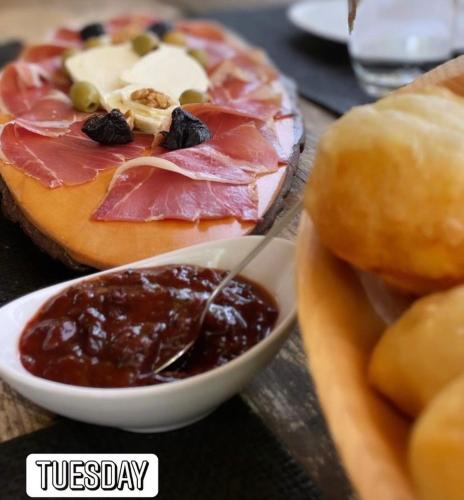 a plate of food with ham and jam and a sandwich at Ethno village & resort Ćorić in Mojkovac