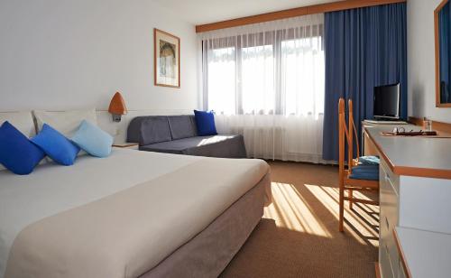 a hotel room with a large bed and a couch at Novotel Poznań Malta in Poznań