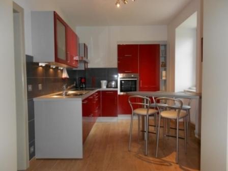 サヴェルヌにあるMeublé de Tourisme 3*の赤いキャビネットとバースツール付きのキッチン