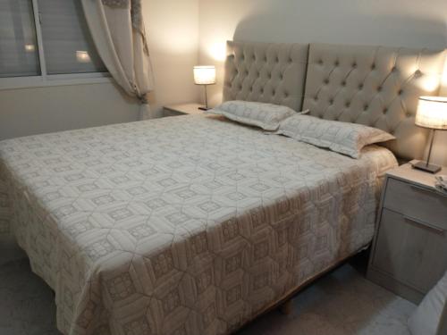 a bedroom with a large bed with two lamps at Temporarios Roque Saenz Peña, Dto D in Puerto Madryn