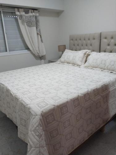 un grand lit blanc dans une chambre avec une fenêtre dans l'établissement Temporarios Roque Saenz Peña, Dto D, à Puerto Madryn