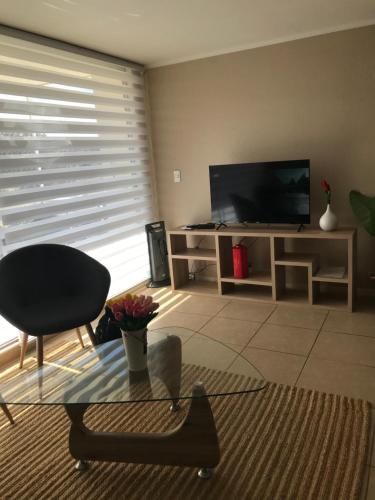 un salon avec une télévision et une table en verre dans l'établissement Laguna Bahía departamento 5 personas maravilloso amoblado y decorado, à Algarrobo