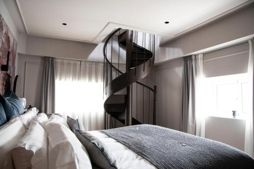 a bedroom with a bed and a spiral staircase at Soho Boutique Palacio de Pombo in Santander