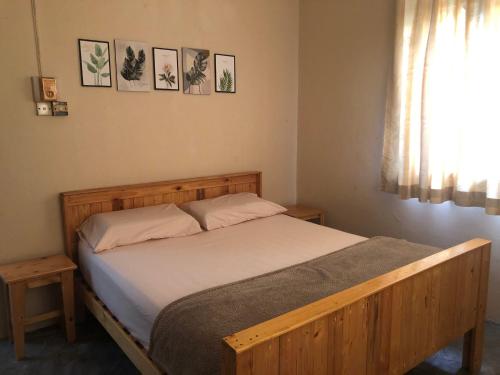 コタバルにあるLittle Cozy Homestayのベッドルーム1室(木製ベッド1台、窓付)