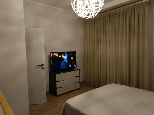 um quarto com uma televisão, uma cama e um lustre em #Butterfly# em San Filippo del Mela