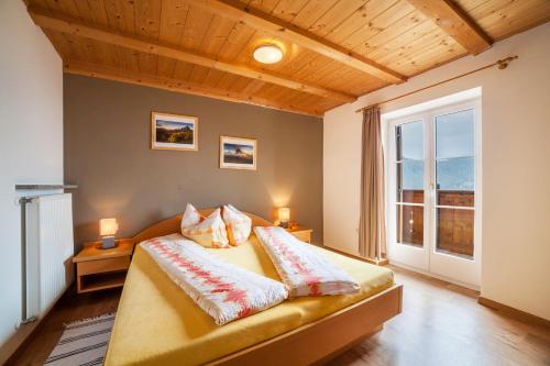 a bedroom with a bed with two pillows and a window at Lingerhof Arnika in Meltina