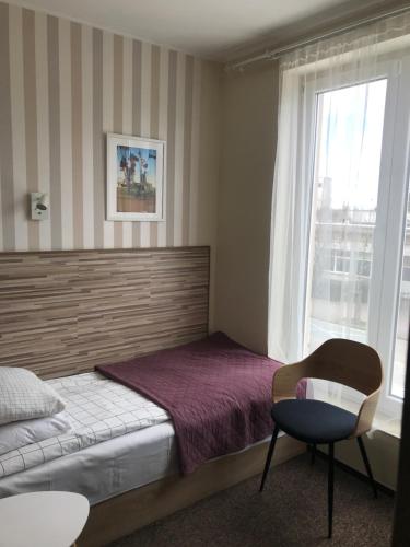 um quarto com uma cama, uma cadeira e uma janela em Fabryka em Sopot